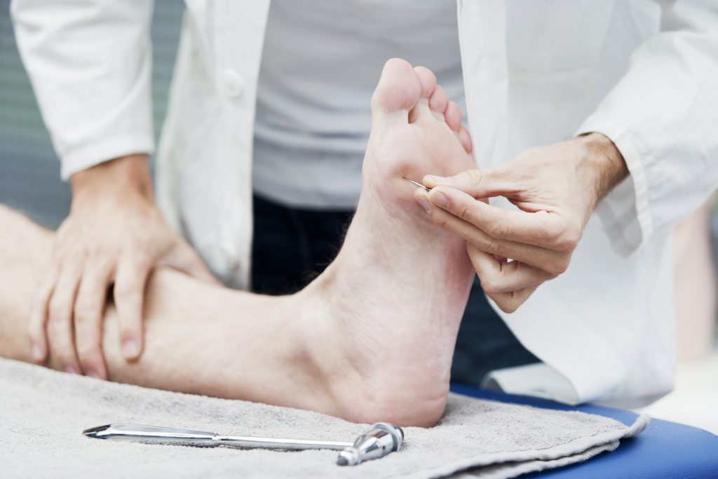 Doctor testing sensation on the sole of a patient's foot