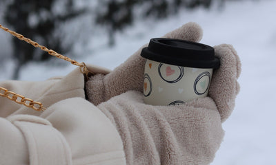 Gloved hands holding a warm drink in the snow