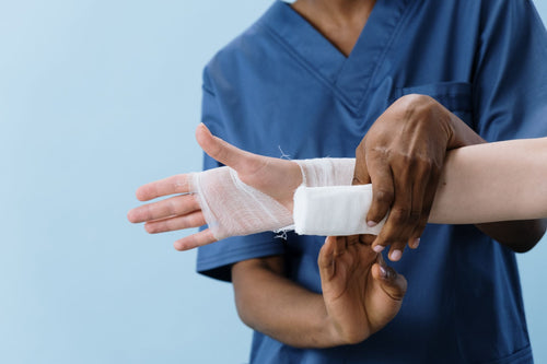 Medical professional wrapping a bandage around a patient's hand